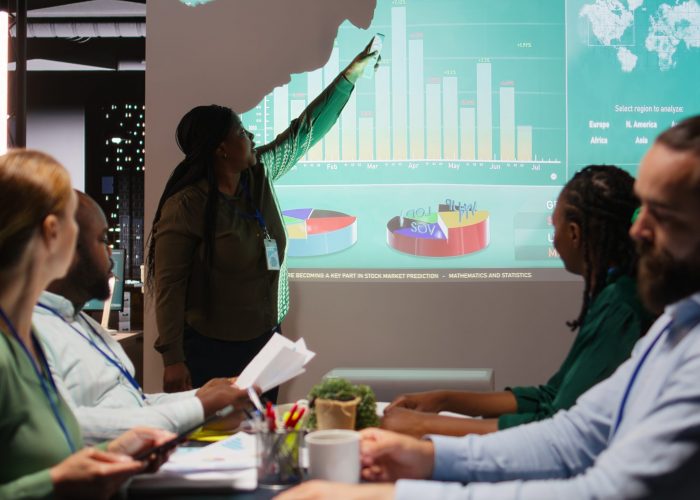 Diverse group of corporate associates look into project timelines and agenda, create a strategy for development after hours in conference room. Goal setting in business environment. Camera A.